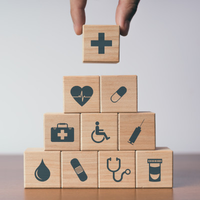 Blocs en bois représentant différents symboles du secteur de la santé et du social, illustrant les enjeux de formation et de recrutement de l’OPCO Santé.