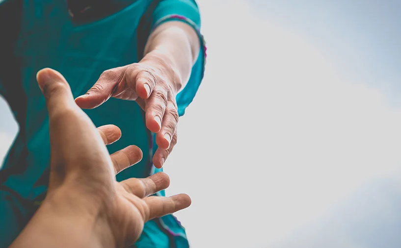 Deux mains se tendent l’une vers l’autre, symbolisant l’aide et le soutien dans les métiers du sanitaire et social