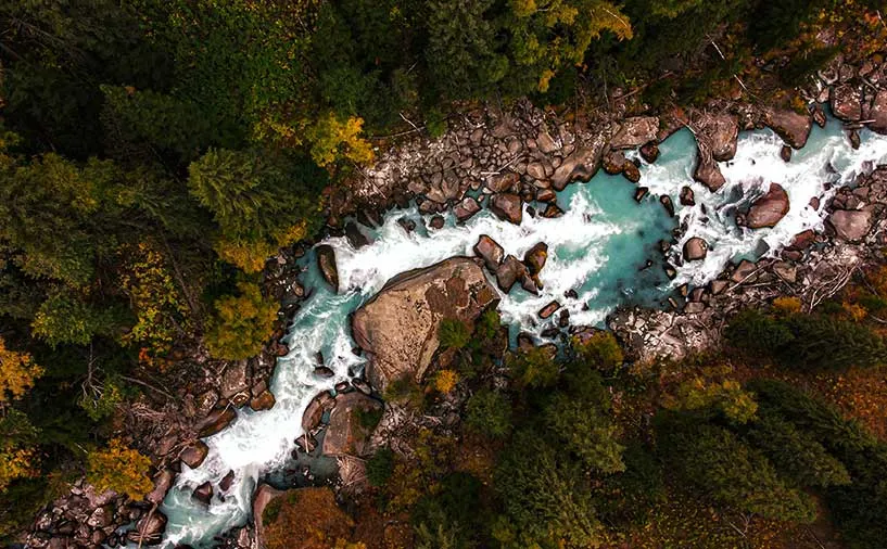 Vue aérienne d’une rivière turquoise traversant une forêt dense avec des rochers