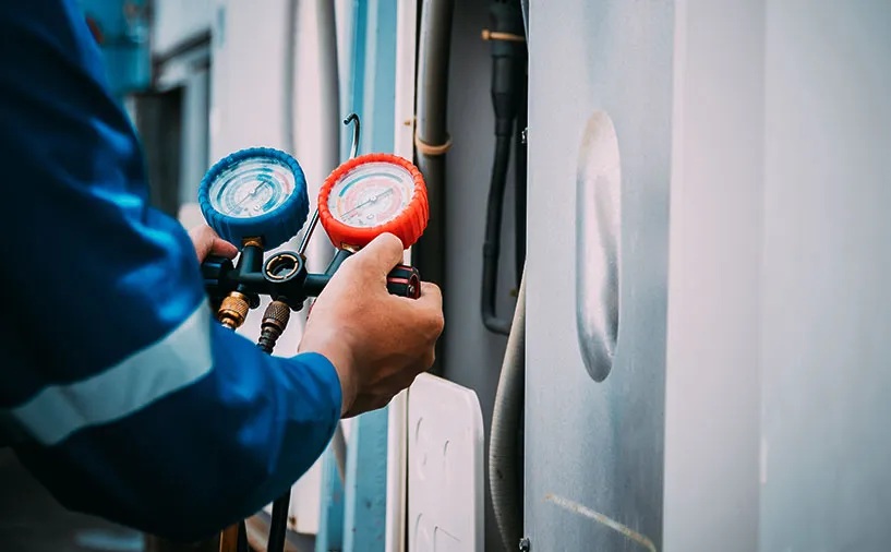 Gros plan sur les mains d’un technicien manipulant des manomètres de contrôle sur une installation géothermique