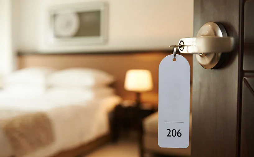 Porte de chambre d’hôtel entrouverte avec une clé portant une étiquette "206", symbolisant le secteur de l’hôtellerie, restauration et du tourisme en Nouvelle-Aquitaine.