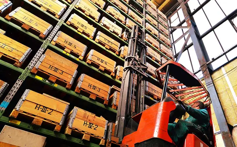 Cariste utilisant un chariot élévateur dans un entrepôt de stockage à hauts rayonnages, illustrant les métiers de la logistique et du transport étudiés par l’observatoire régional emploi-formation de Cap Métiers Nouvelle-Aquitaine.