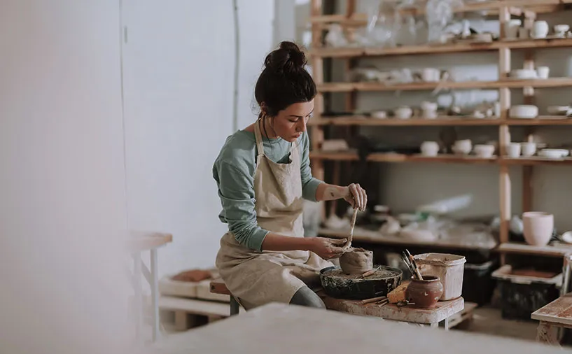 Jeune femme en tablier travaillant la céramique dans un atelier artisanal