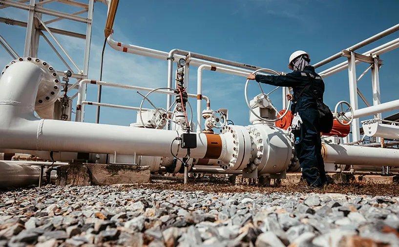 Technicien en tenue de sécurité effectuant une opération sur une installation industrielle dans un environnement sensible.