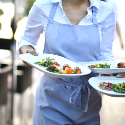 Une serveuse porte des plats dans un restaurant