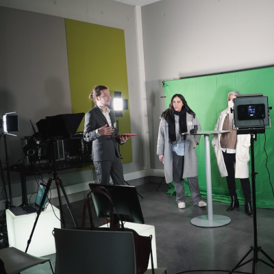 Scène de tournage vidéo avec fond vert et participants.