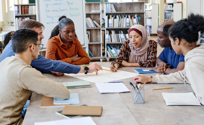 Groupe de personnes assis autour d'une table et apprenant le français