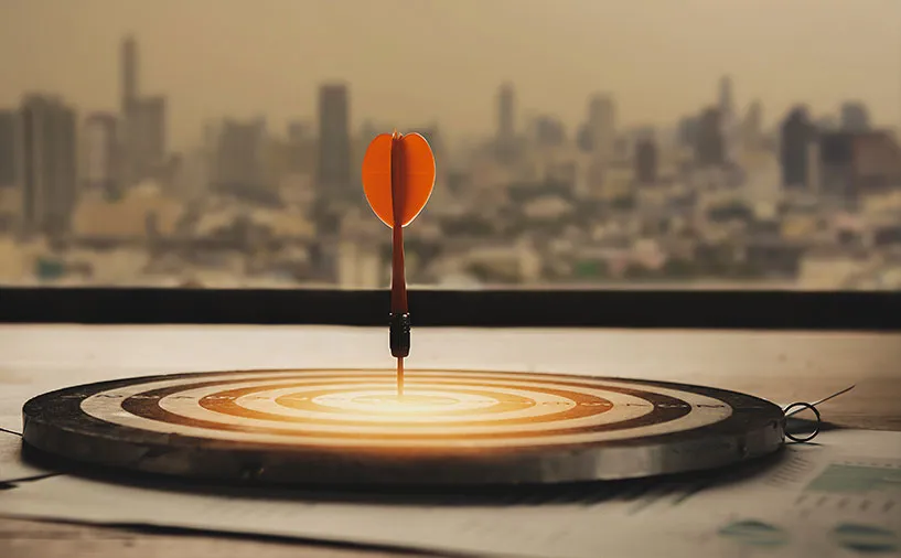 Fléchette atteignant le centre d’une cible avec une ville en arrière-plan, symbolisant la précision et la stratégie